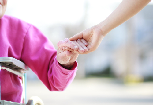 senior lady in wheelchair holding hand