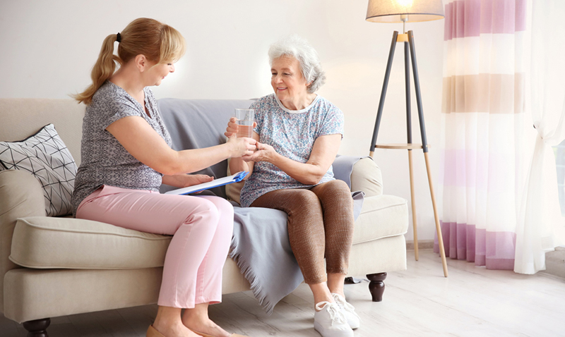 caregiver offering glass of water to senior