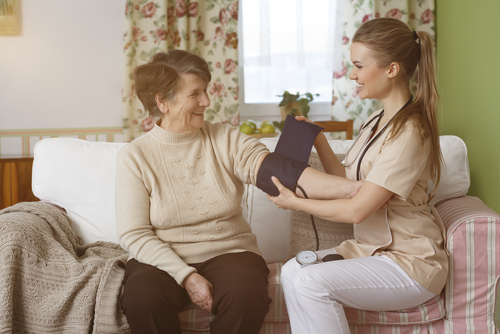 Happy nurse measuring blood pressure